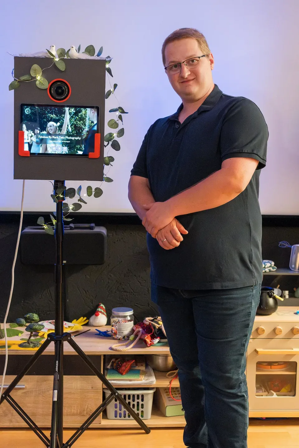 Mark Tietz neben seiner Hochzeits-Fotobox mit Eukalyptus-Deko, Touchscreen und Studioblitz